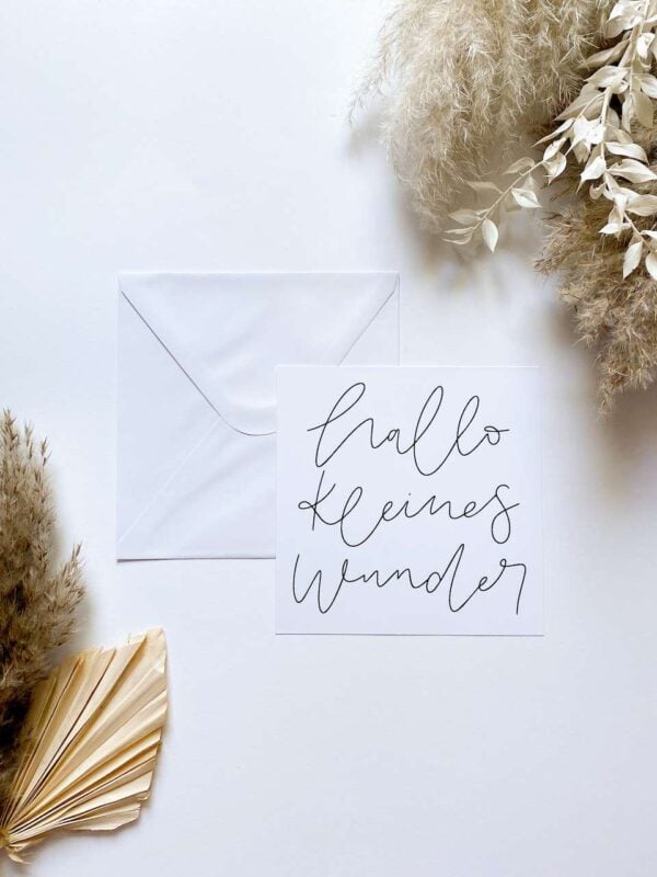 Besinnliche Grußkarte mit Schriftzug "hello kleines Wunder" und weißen Deko-Elementen.