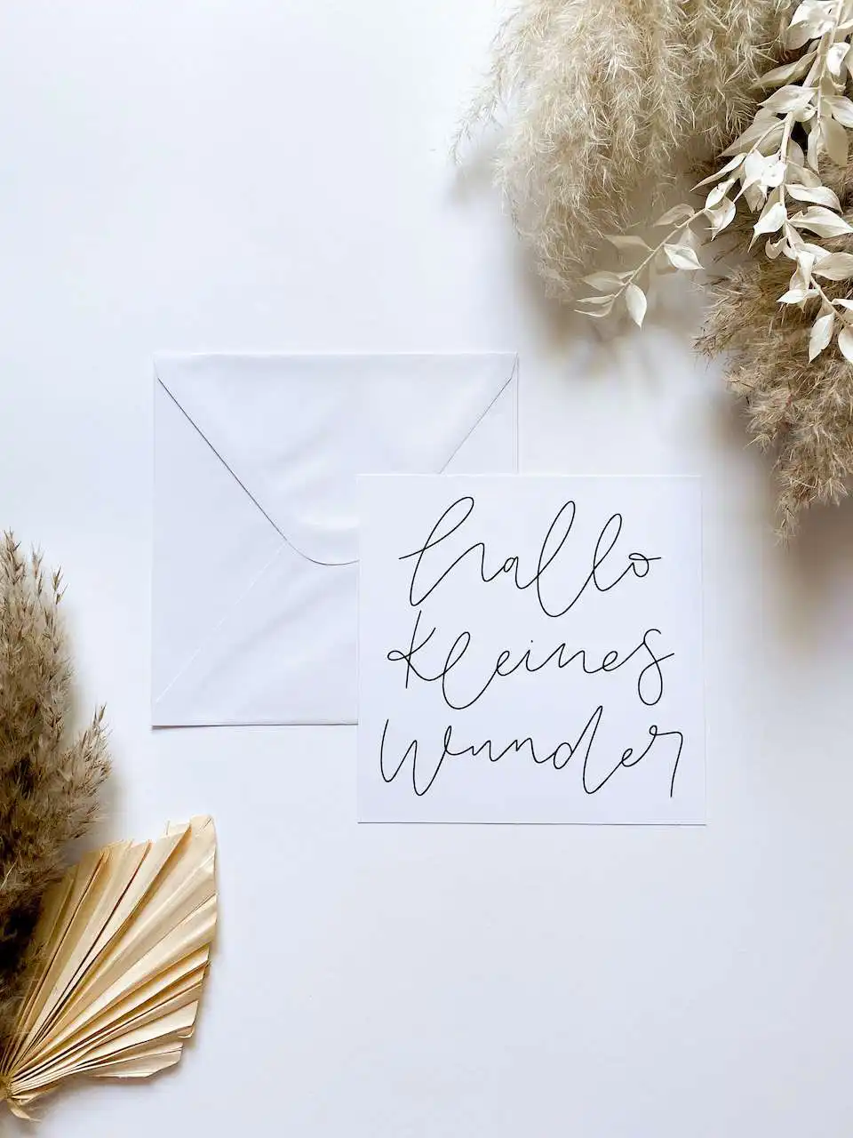 Besinnliche Grußkarte mit Schriftzug "hello kleines Wunder" und weißen Deko-Elementen.