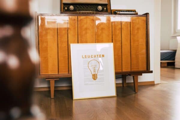 Vintage Holzsideboard mit Leuchten-Poster im Wohnzimmer.