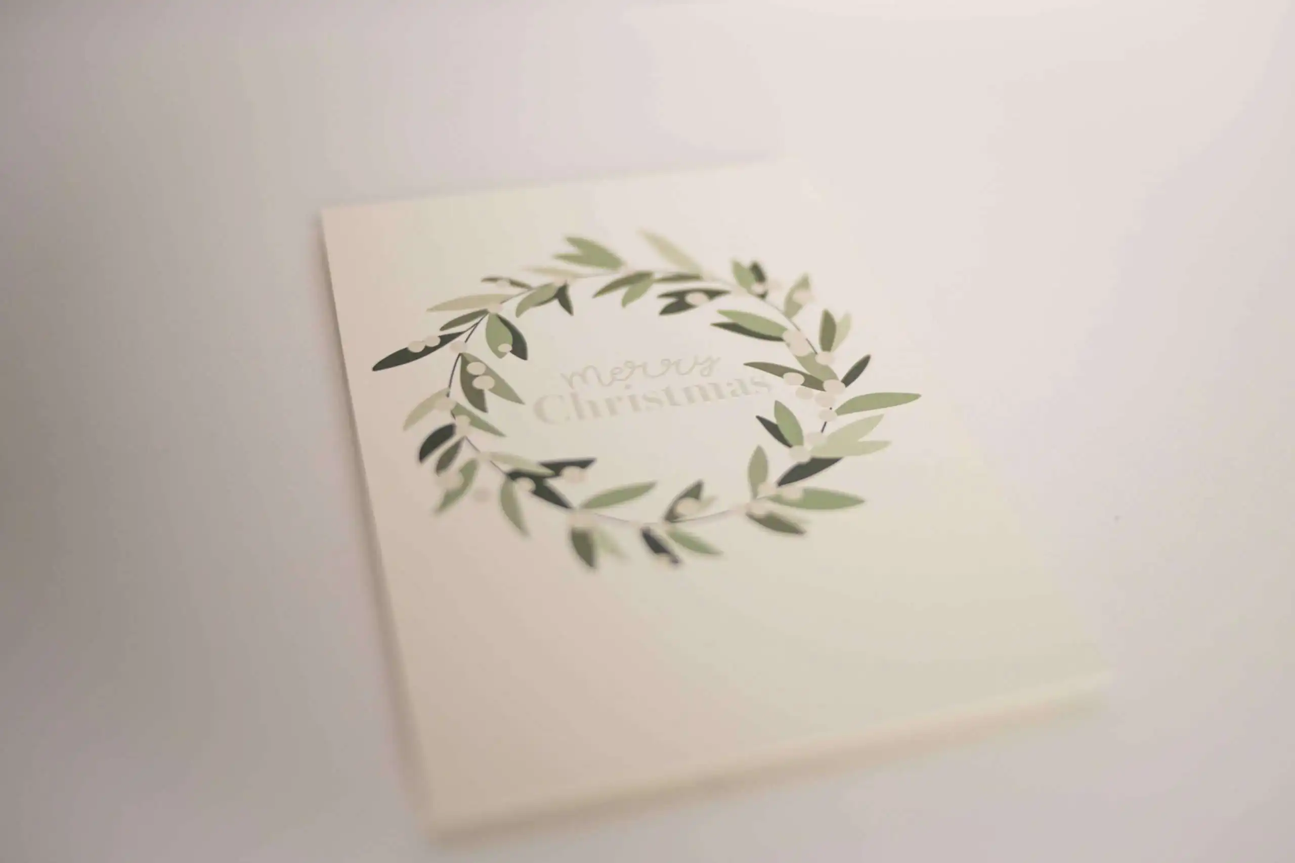 Stilvolle Weihnachtskarte mit grünem Kranz und 'Merry Christmas' Schriftzug.