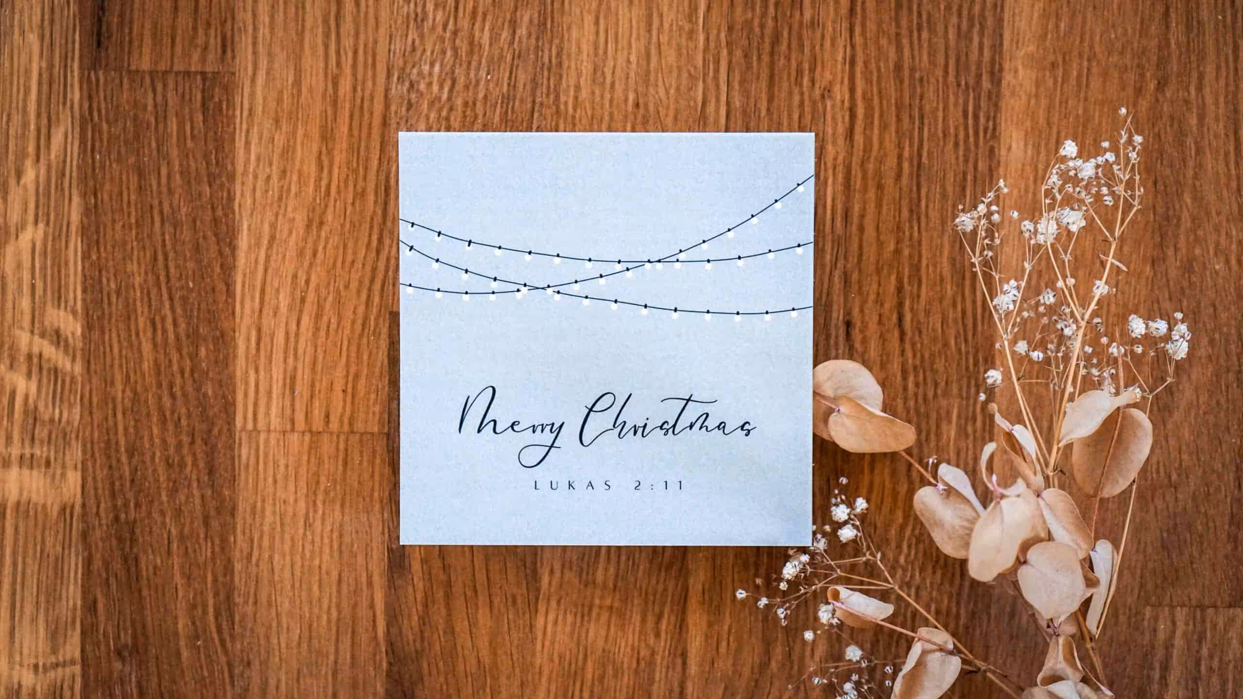 Frohe Weihnachtskarte mit Bibelvers Lukas 2:11 auf Holzoberfläche, stilvoll und festlich.