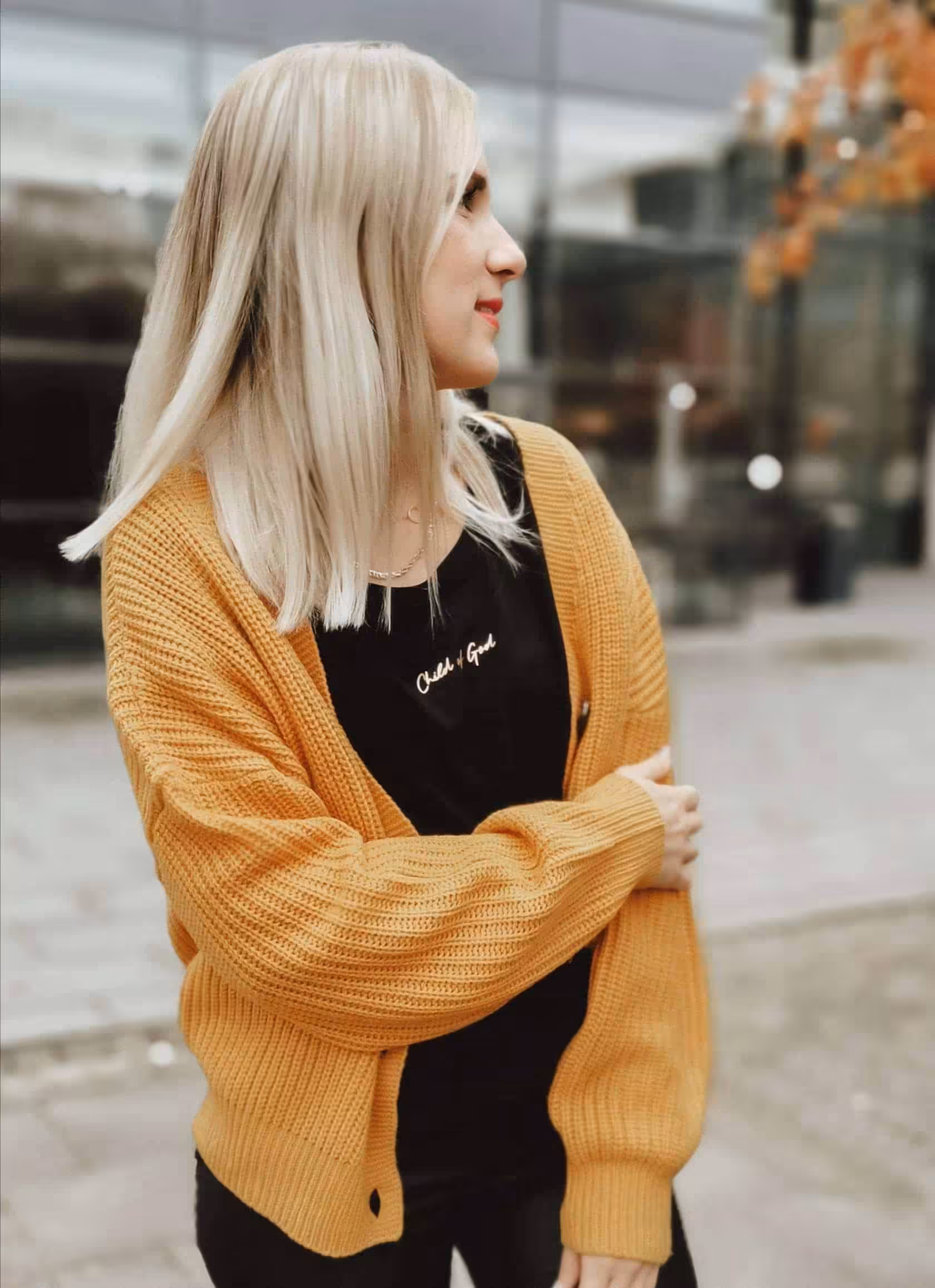 Moderne junge Frau trägt gelbe Strickjacke, streetstyle Look, Stadt, Mode, Lifestyle.