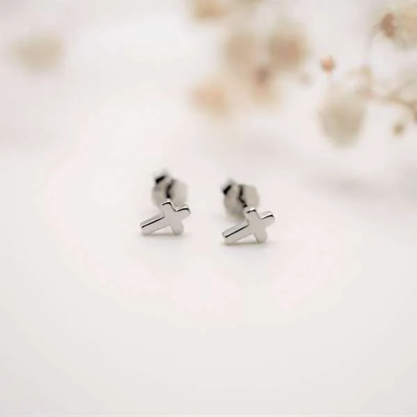 Minimalistische christliche Kreuz-Ohrstecker aus 925 Sterling Silber von FIRSTGOD bei mookho liegen auf einem weißen Tuch.