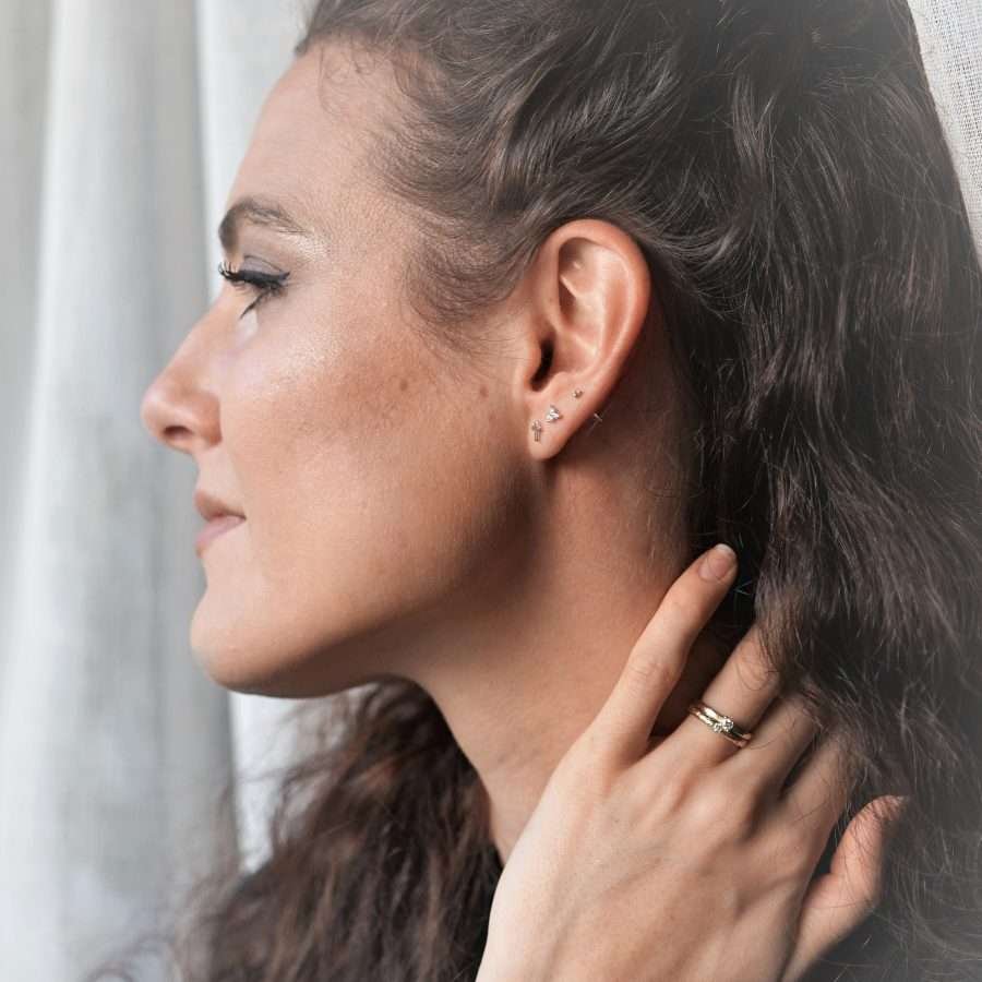 Minimalistische TRINITY Ohrstecker von FIRSTGOD aus 925 Sterling Silber mit funkelnden Glitzersteinchen, werden von einer Frau am Ohr getragen.