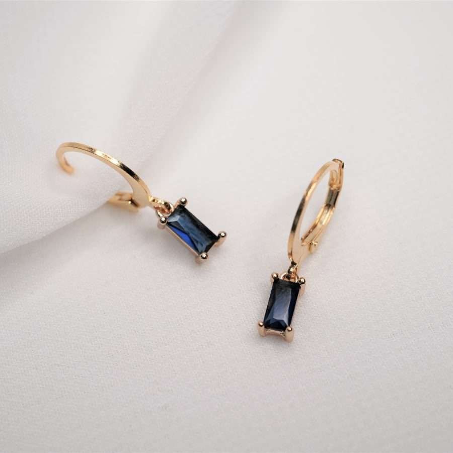 Moderne 24k Gold beschichtete christliche Ohrringe Hoop DIANA von FIRSTGOD bei mookho mit edlem Schmuckstein, liegen auf einem weißen Tuch.
