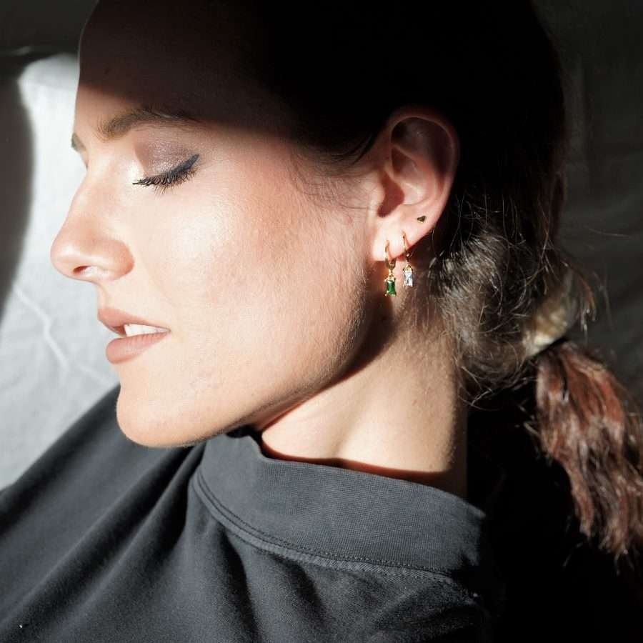 Moderne 24k Gold beschichtete christliche Ohrringe Hoop DIANA von FIRSTGOD bei mookho mit edlem Schmuckstein, werden von einer Frau am Ohr getragen.