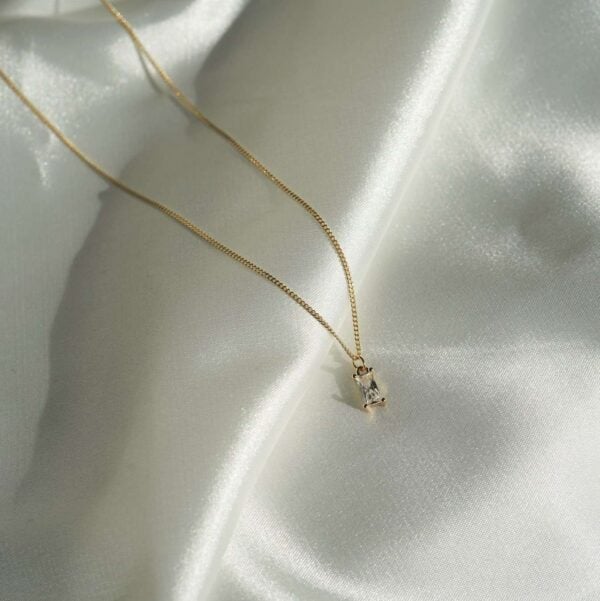 Funkelnder goldener Kettenanhänger mit Schmuck auf glänzendem Satinstoff.