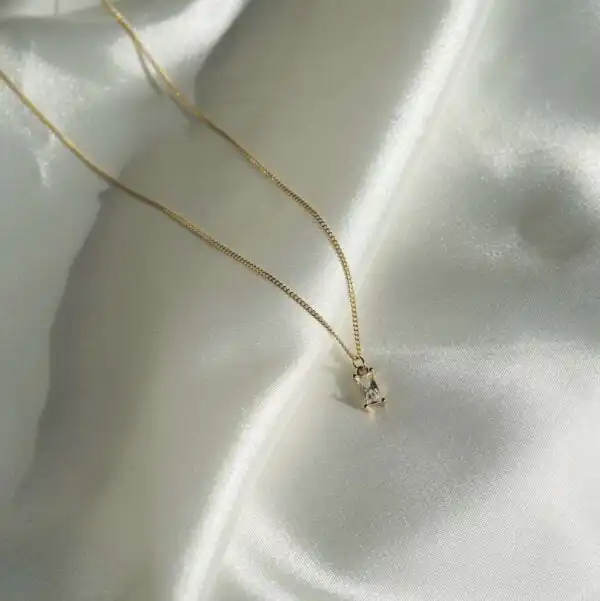 Funkelnder goldener Kettenanhänger mit Schmuck auf glänzendem Satinstoff.