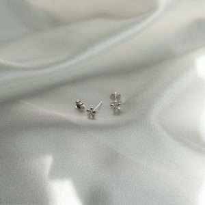 Das Bild zeigt die christlichen Ohrstecker FLEUR MINI von FIRSTGOD bei mookho. Die Ohrstecker liegen einzeln auf einem weißen Tuch.