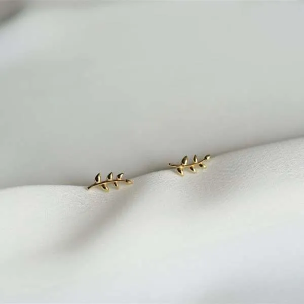 Das Bild zeigt die christlichen Ohrstecker LEAVE MINI von FIRSTGOD bei mookho, die elegant auf einem weißen Tuch liegen.