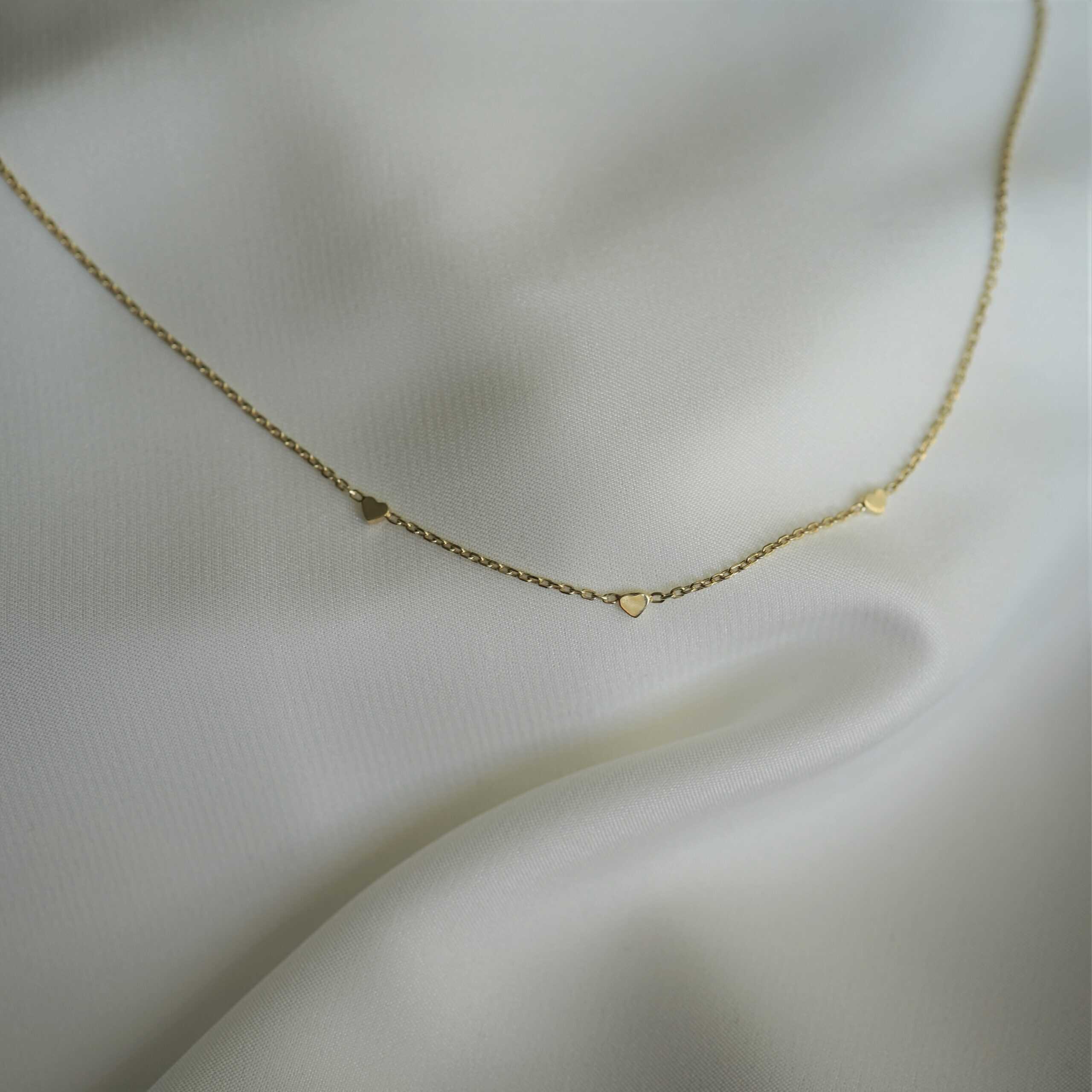 Endless Love | Christliche Kette – 925 Sterling Silber vergoldet – 42cm Länge – gold/roségold/silber 5 Zarte goldene Halskette mit Herzanhängern auf weißem Satin-Hintergrund.