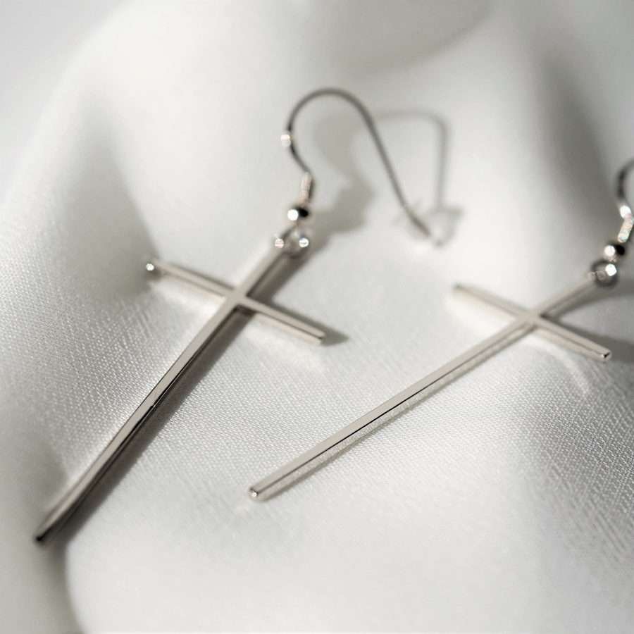 Minimalistische christliche Ohrringe SLIM CROSS von FIRSTGOD bei mookho aus 925 Sterling Silber, liegen auf einem weißen Tuch.