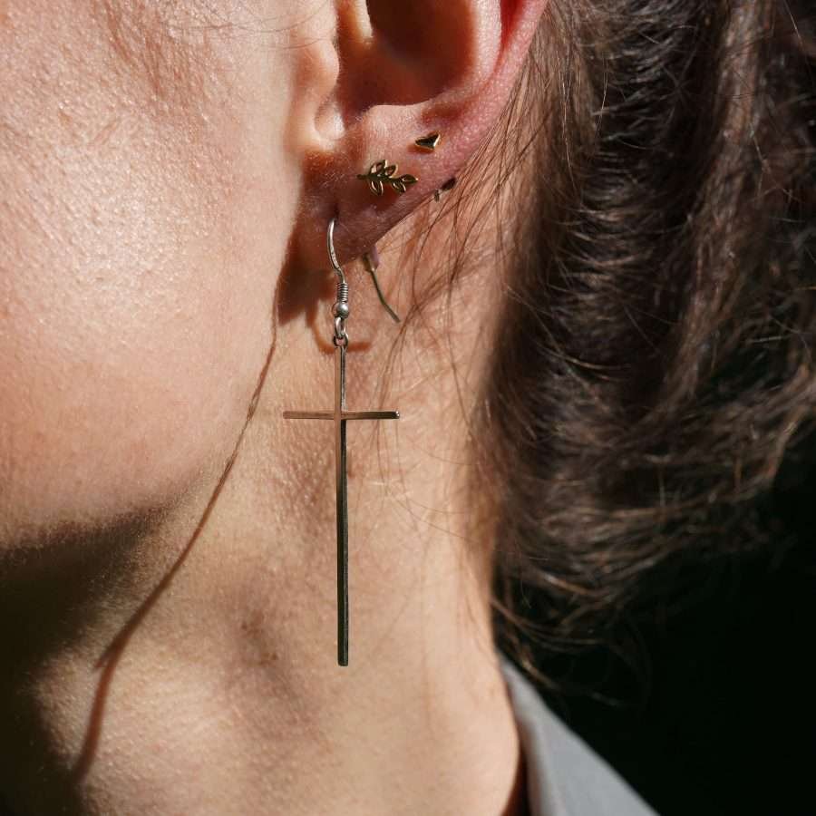 Minimalistische christliche Ohrringe SLIM CROSS von FIRSTGOD bei mookho aus 925 Sterling Silber, werden von einer Frau am Ohr getragen.