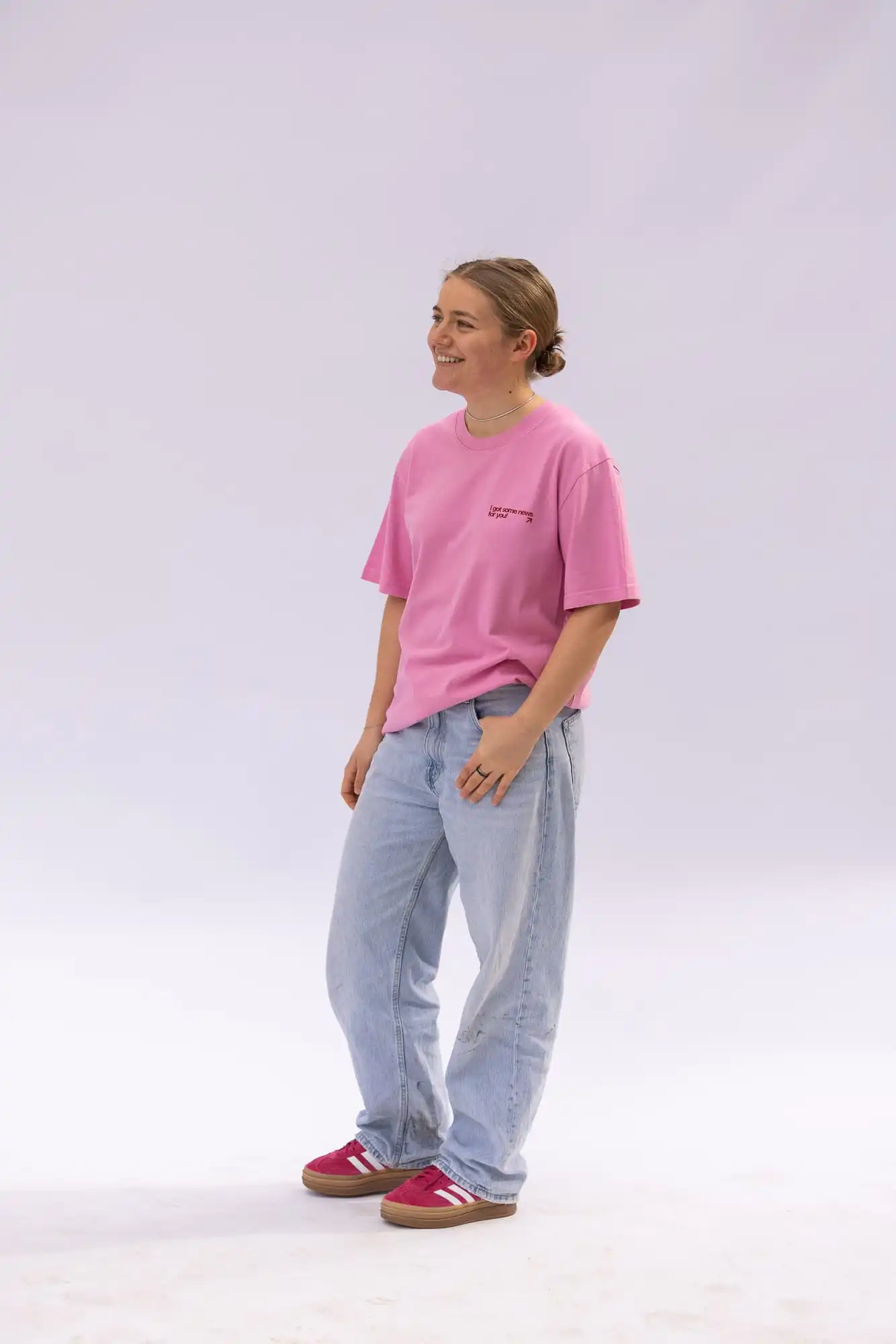 Good News | Christliches T-Shirt – 100 % Bio-Baumwolle – bubble pink – oversized 3 Inspirational Christliche Mode, junge Frau im pinken T-Shirt und Jeans, nackte Beine, lächelnd, casual, christlicher Markenmarketplace.