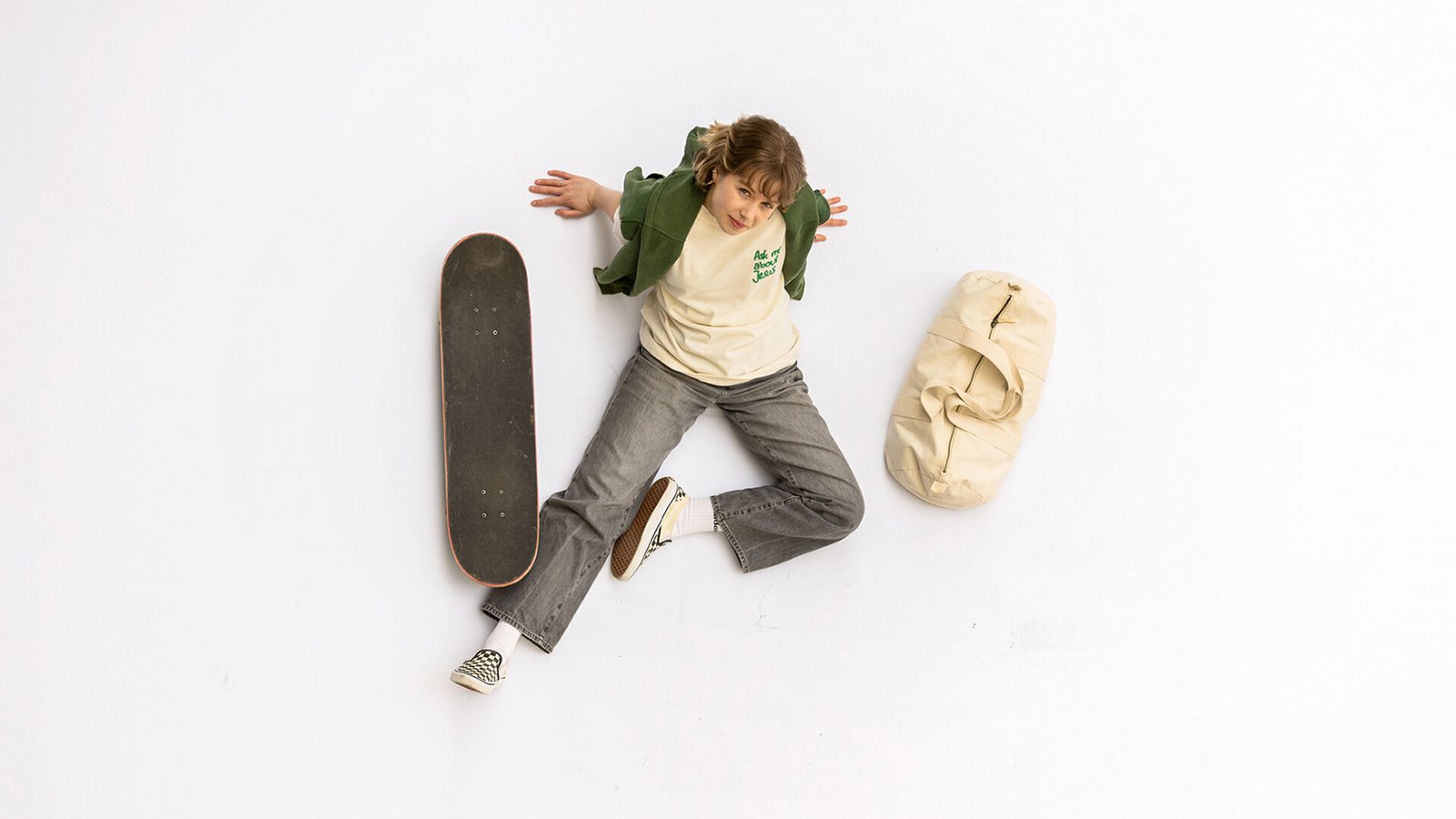 Ask me about Jesus Shirt von Radiant Clothing. Junges Mädchen sitzt mit Skateboard und Tasche auf dem Boden.
