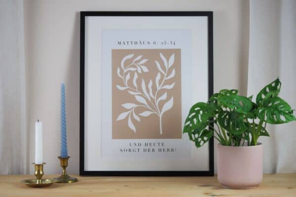 Moderner christlicher Spruchrahmen auf dekorativem Holzschreibtisch mit Zimmerpflanze und Kerzen.