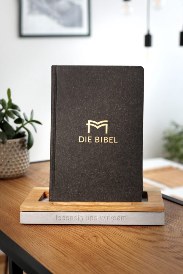 Die Bibel ist aufgestellt und präsentiert. Im Hintergrund ist ein Esstisch zu sehen.