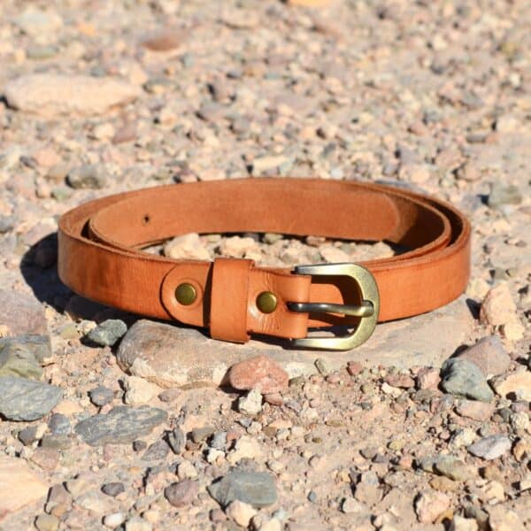 Leder-Gürtel mit Schnalle auf Kieselsteinboden, christliche Mode, langlebiges Accessoire.