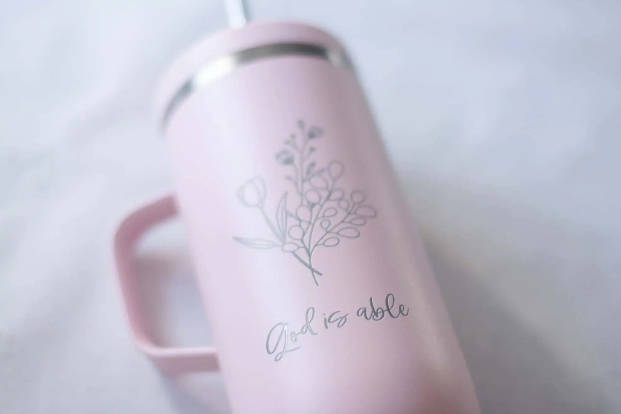 Christlicher Thermobecher aus recyceltem Edelstahl mit Gravur 2 Blumenmuster auf pinker Tasse mit christlicher Botschaft "God is able".
