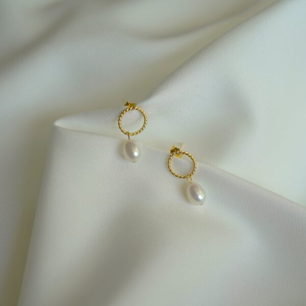 Elegante goldene Ohrringe mit Perlen, christliches Schmuckdesign.