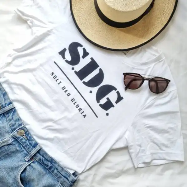 Stylisches T-Shirt mit christlichem Logo, Sonnenbrille, Hut auf weißem Hintergrund.