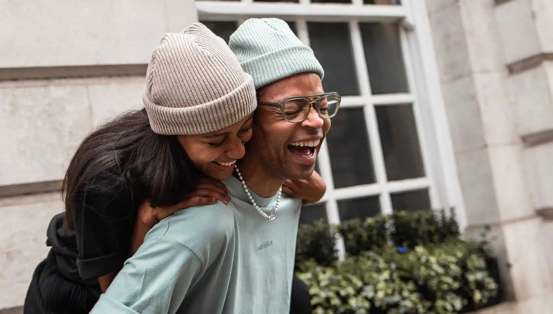 Zwei glückliche Freunde in individuell produzierter Kleidung von mookho – Beanies und Shirts selbst designed.