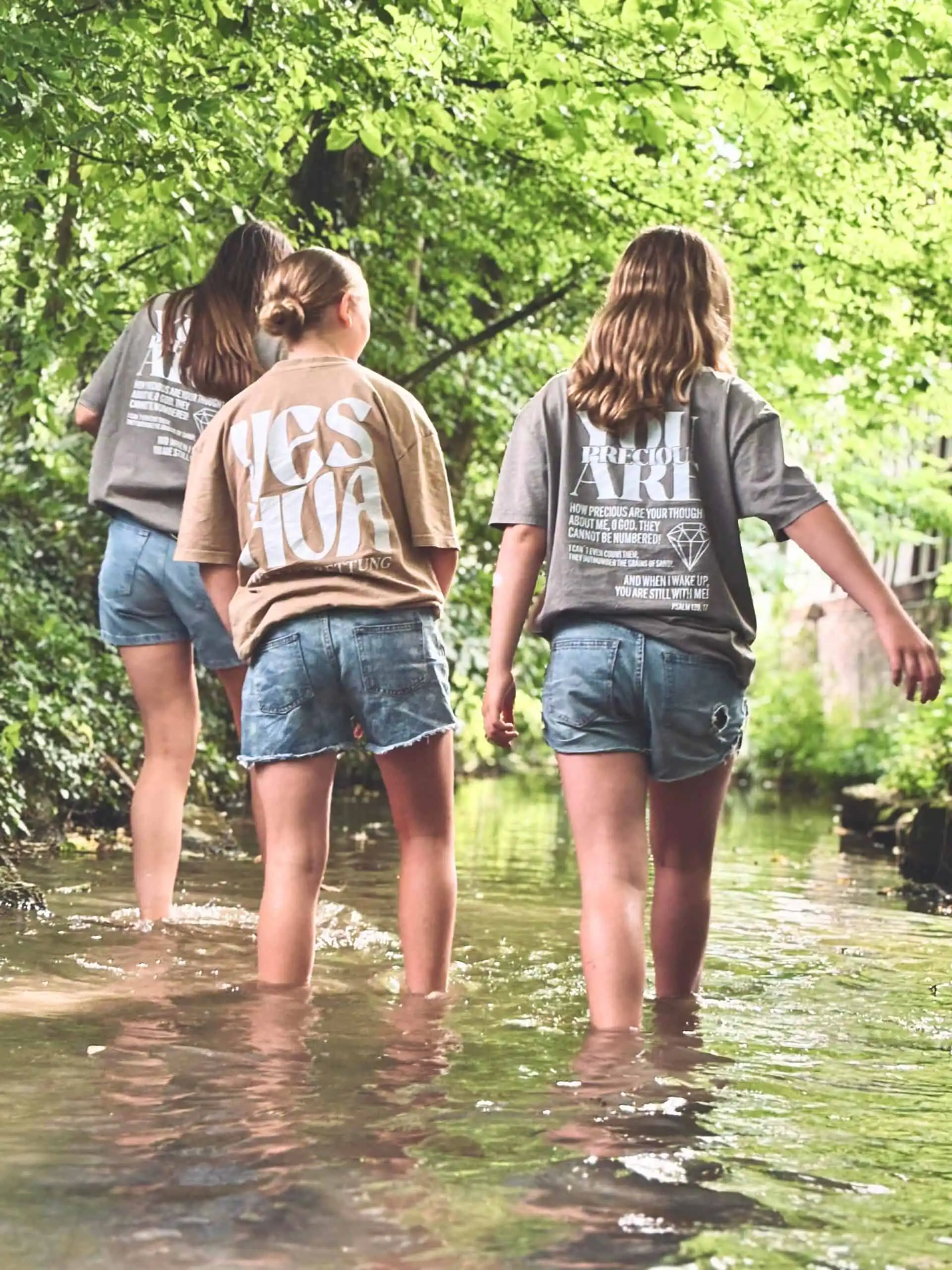 Fröhliche Mädchen beim Wasserspiel in der Natur, christliche Mode für Kinder, nachhaltige Kleidung.