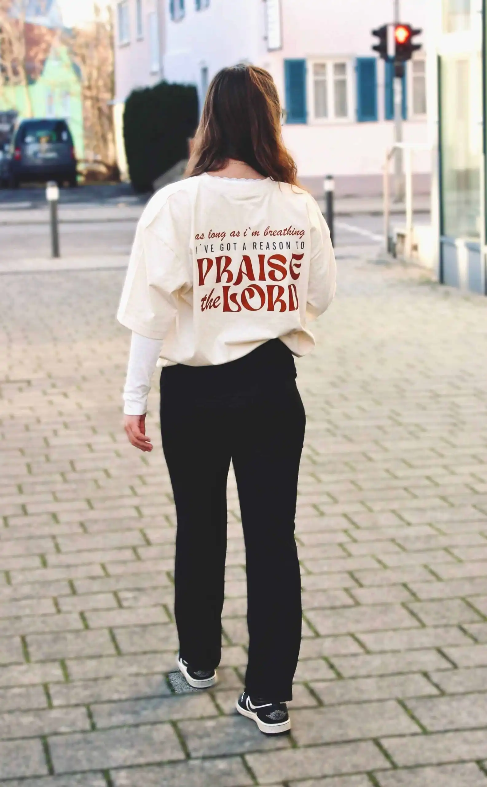 Hände, die ein christliches T-Shirt für Männer tragen, mit Text "Praise the Lord".