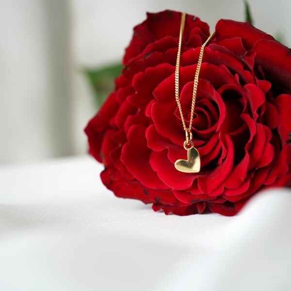 Halskette mit Herz-Anhänger auf roter Rose, christliche Schmuckkunst, Geschenke für Christen.