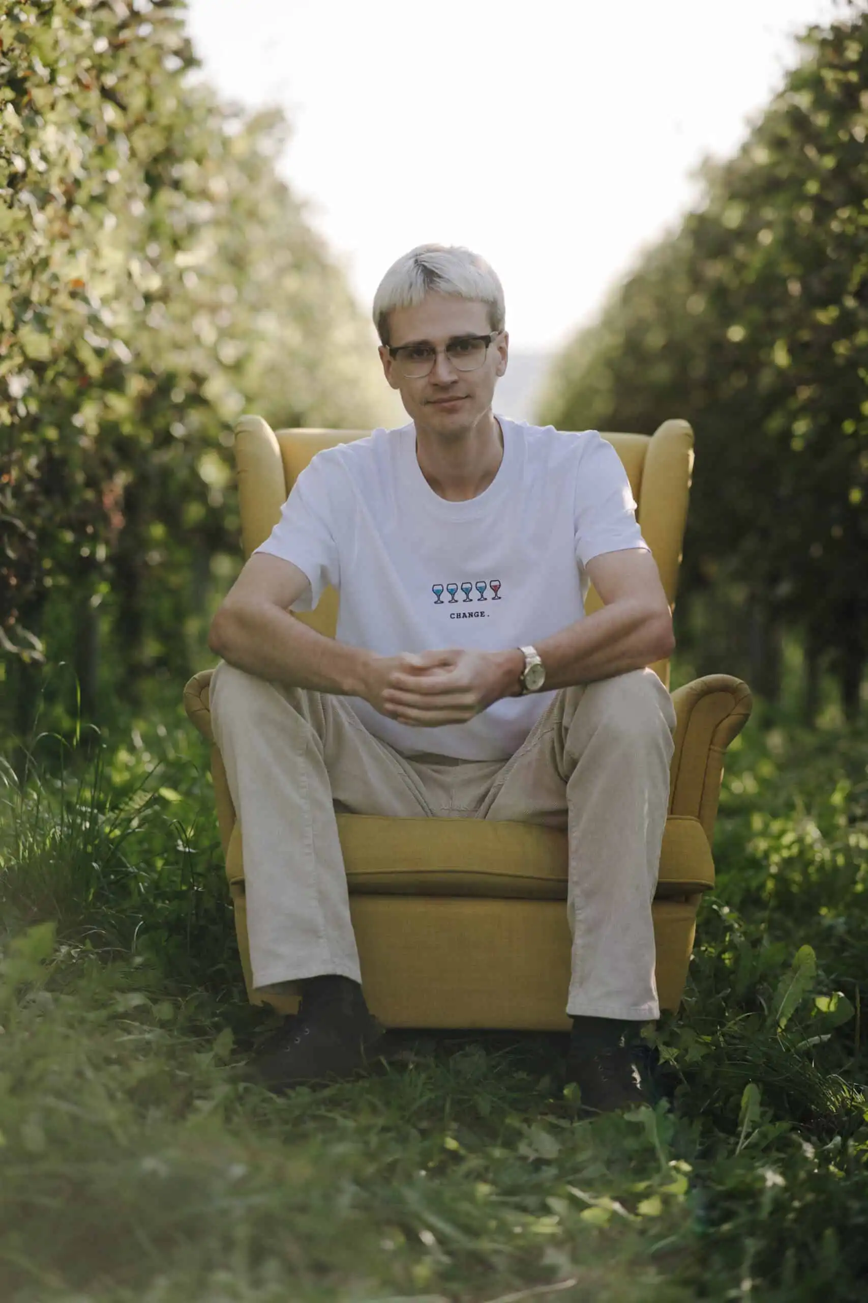 T-Shirt CHANGE | Unisex 3 Lebensstil-Blogger in einem Feld sitzt auf einem gelben Sessel, natürliche Umgebung, entspannte Atmosphäre.