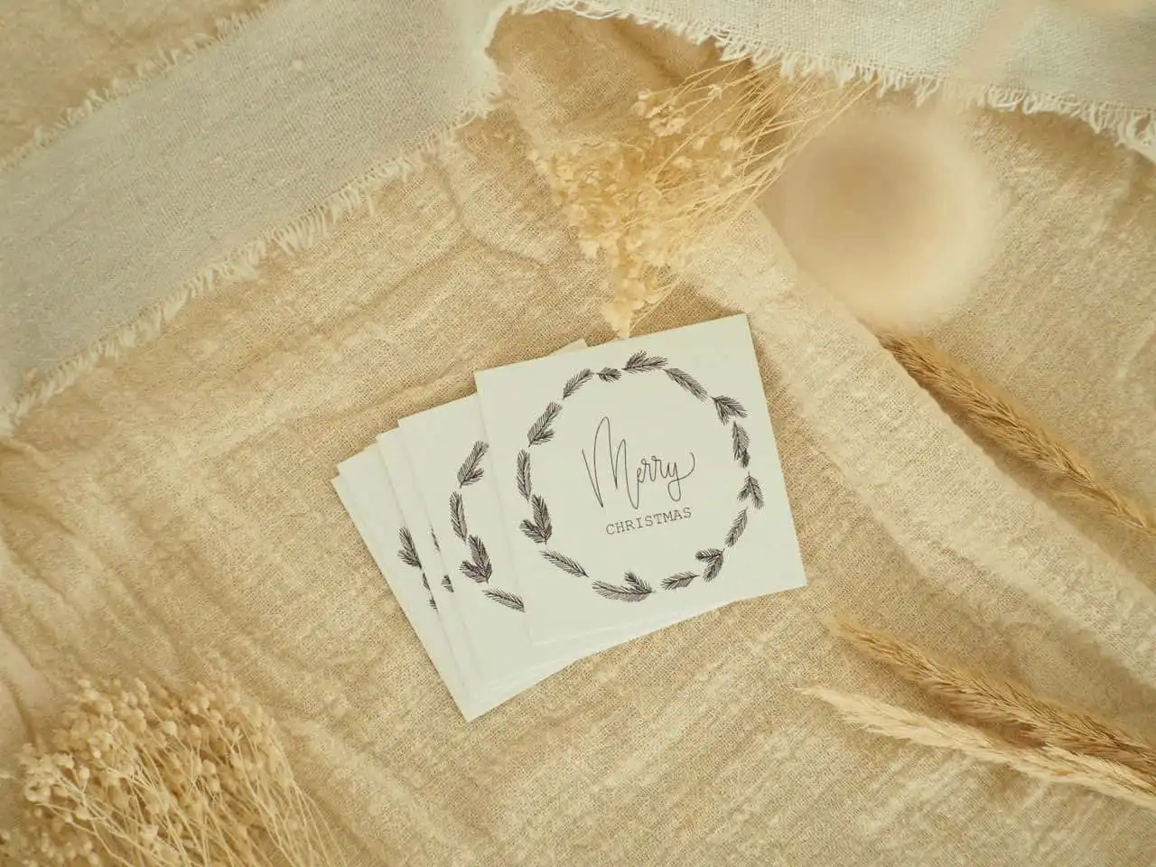 Handgemachte Weihnachtskarten mit christlichem Gruß auf natürlichem Stoffhintergrund.
