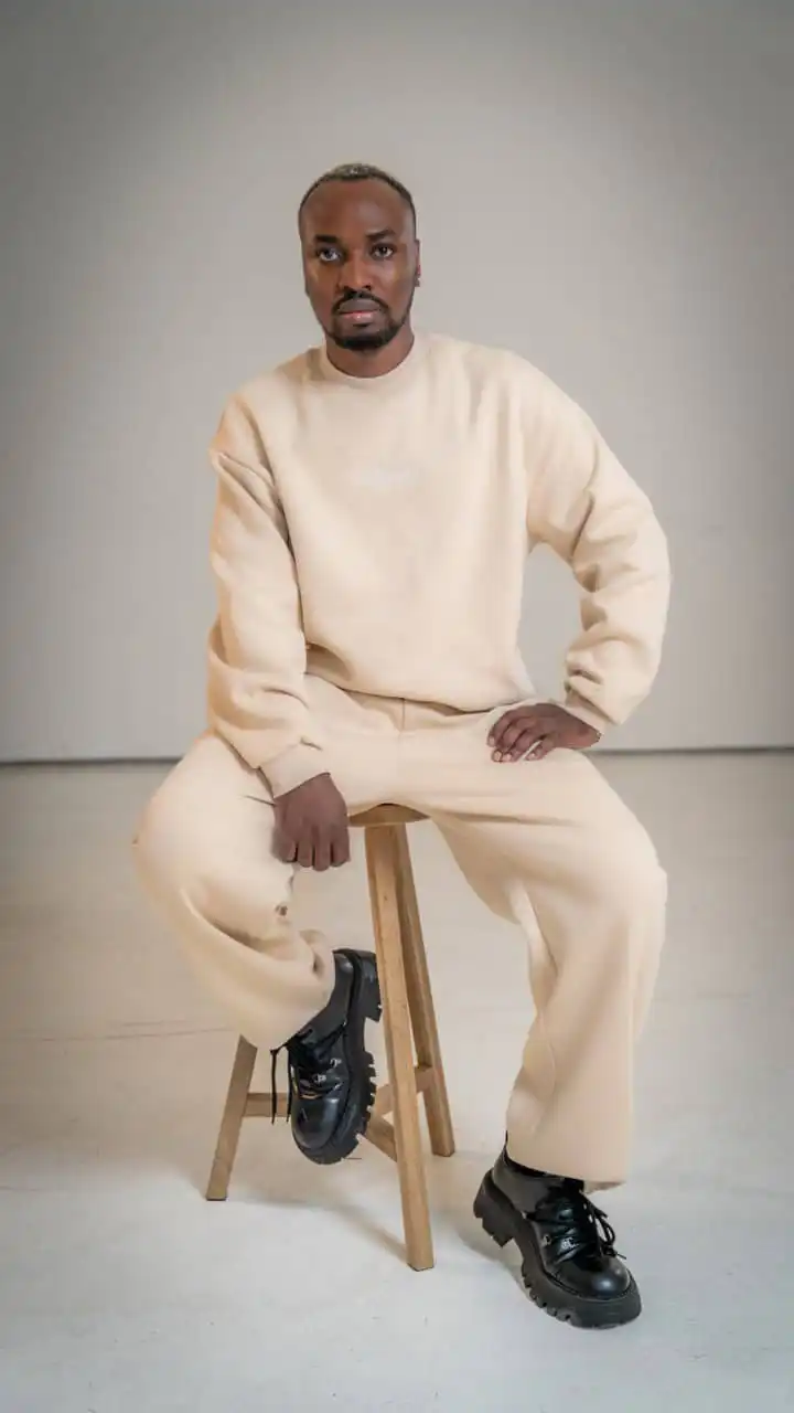 Essential Sweatshirt Oversized - "Paulus" 5 Moderner Mann in beiger Kleidung auf Hocker, christliche Mode, christliche Marken, Glaube.