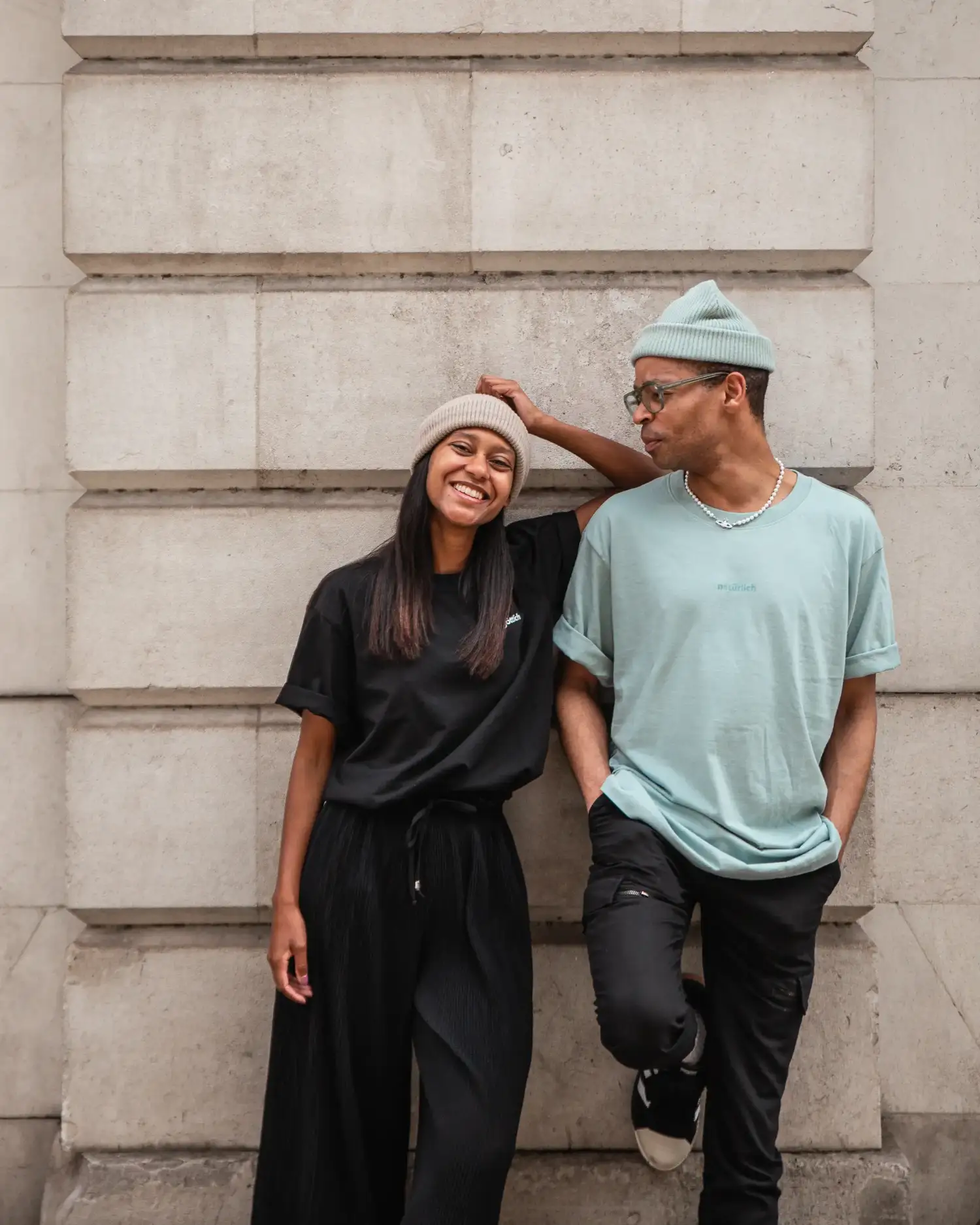 Models lehnen an der Mauer mit schwarzem und petrol farbenen christlichem Shirt