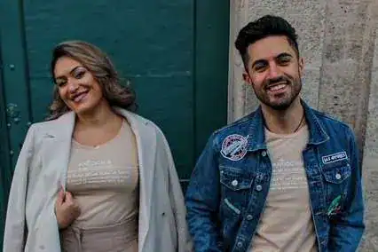 Lächelndes junges Paar vor urbaner Kulisse in trendiger Kleidung.