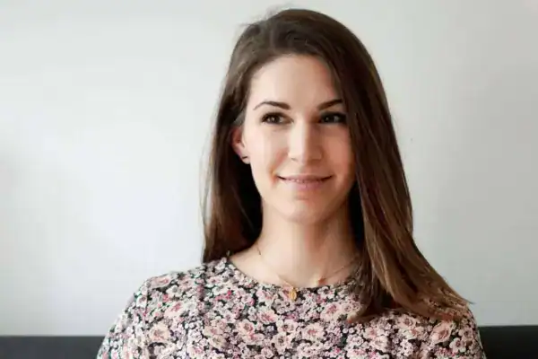 Stilvolle junge Frau mit lockerer Frisur vor hellem Hintergrund.