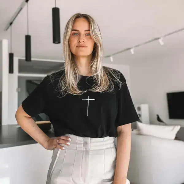Mädchen trägt schwarze T-Shirt mit Kreuzsymbol, modernes Interior, Lifestyle Bild.