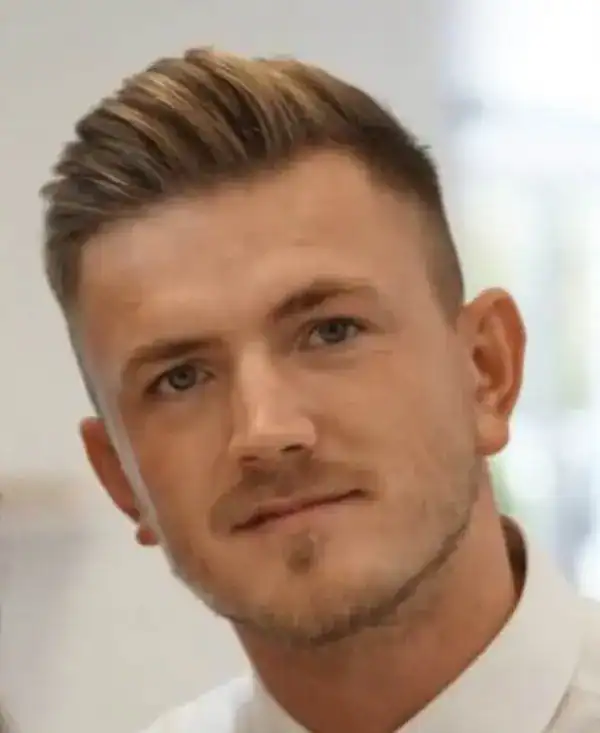 Junger Mann mit modischer Frisur und gepflegtem Bart, freundliches Lächeln, Business-Style.