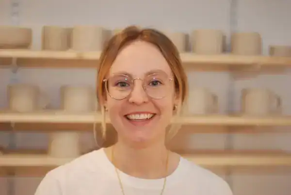 Fröhliche Frau in einer Keramikwerkstatt, staubfreie Arbeitsumgebung, kreative Tätigkeiten.