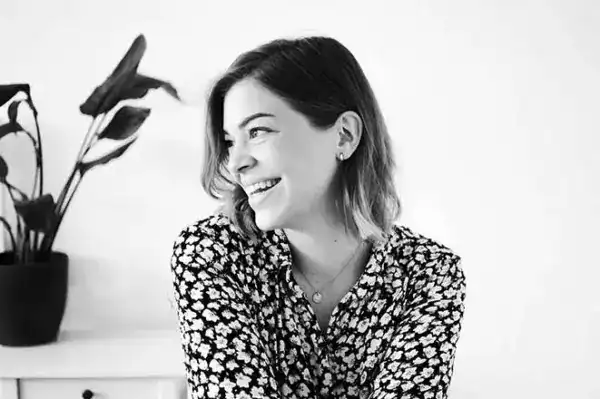 Fröhliche junge Frau mit Blumenmuster-Hemd, lächelnd, natürlicher Look.