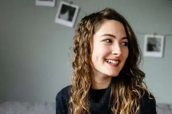 Leichte junge frau mit lockigem braunem haar und lächeln, portraits, freundliches gesicht.