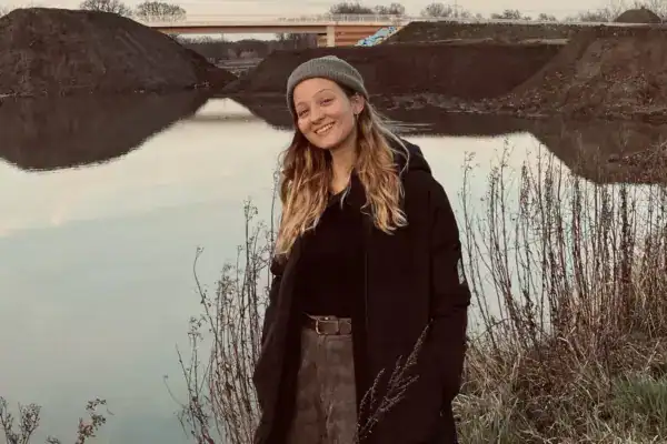 Schöne junge Frau am Flussufer bei Sonnenuntergang in der Natur.