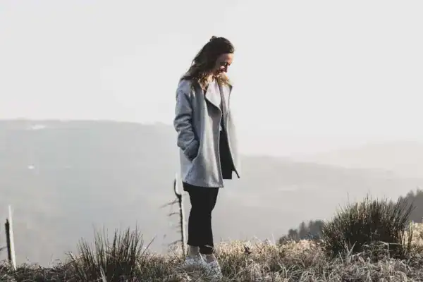 Stilvolle Frau im grauen Mantel beim Spaziergang in der Natur, Bergblick, Outdoor-Mode.