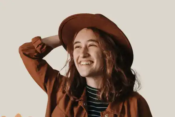 Gemütliche junge Frau mit Cowboyhut und Lachen, entspannt und stilvoll.