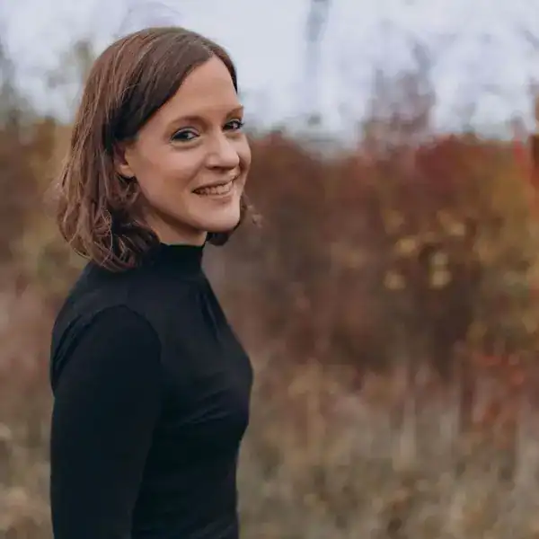 Fröhliche Frau im Herbstlaub, Naturfotografie, Lifestyle, authentisch, warmes Licht.