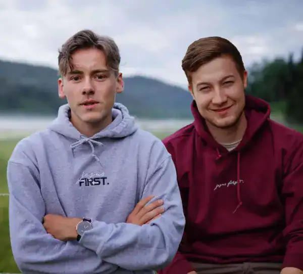 Junge Männer im Freizeitlook mit Hoodies vor Naturkulisse.