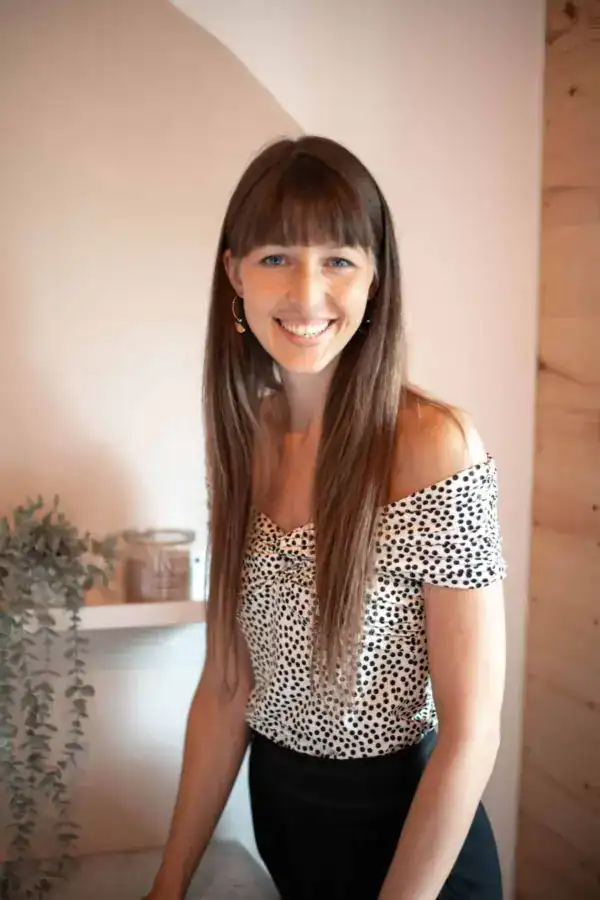 Frau mit braunen haaren und polka-dots-bluse, lächelnd, natürliches licht, interieur, mookho.de, SEO-optimiert.