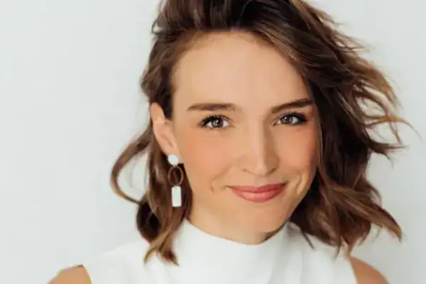 Hochwertige Porträtaufnahme einer jungen Frau mit lockigem Haar und natürlicher Ausstrahlung.