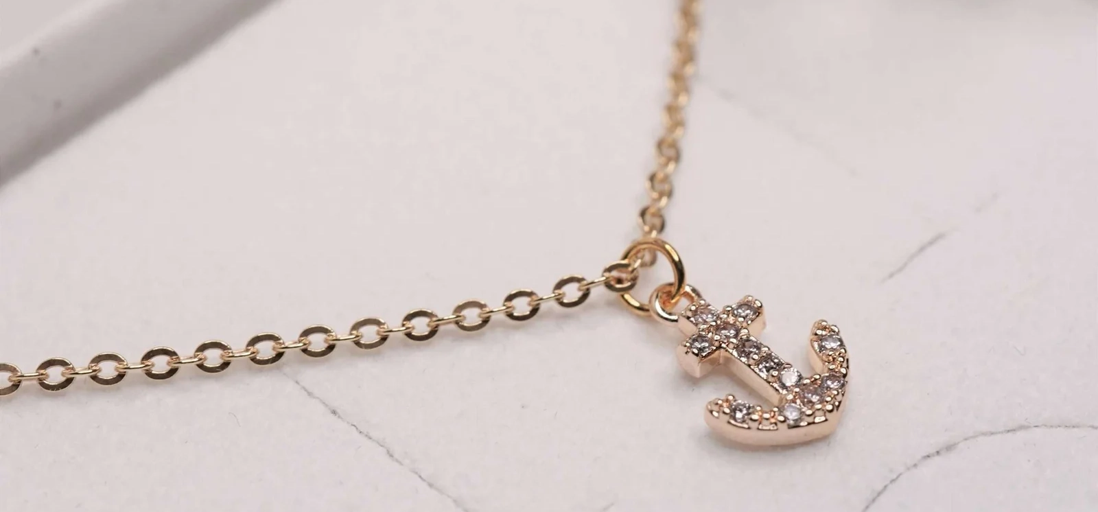 goldene Halskette mit Anker-Anhänger liegt in der Hülle