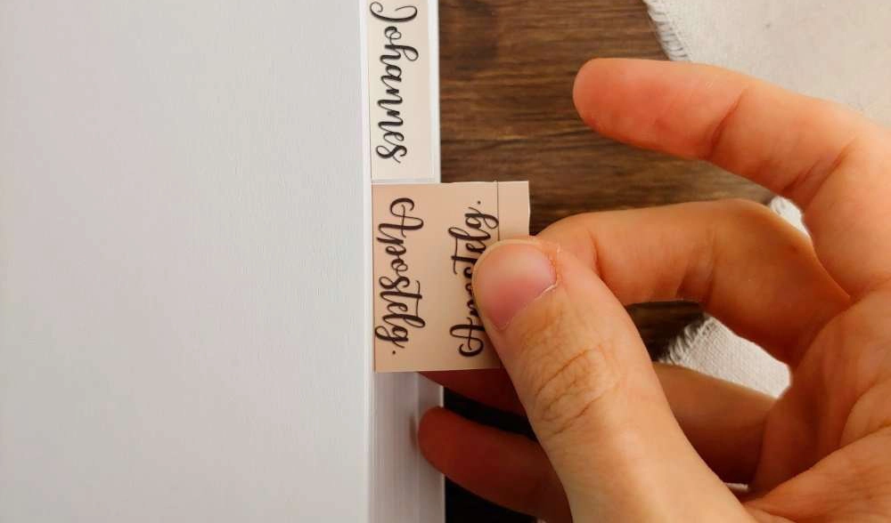 Christliches Bibelregister wird von Hand in eine Bibel eingeklebt