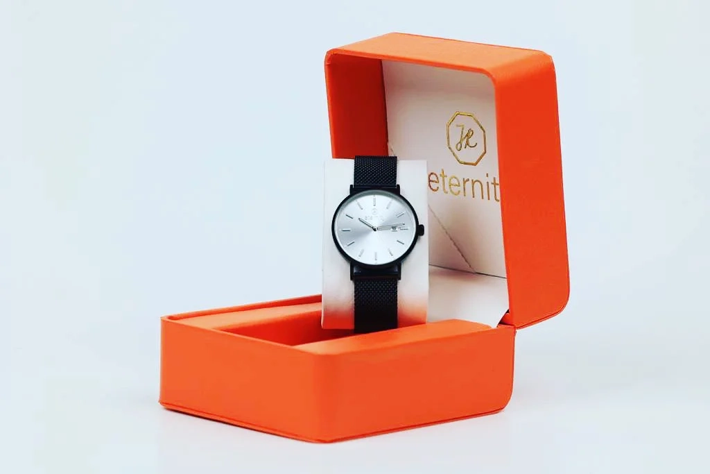 Schwarze christliche Uhr wird in orangenfarbiger Box präsentiert